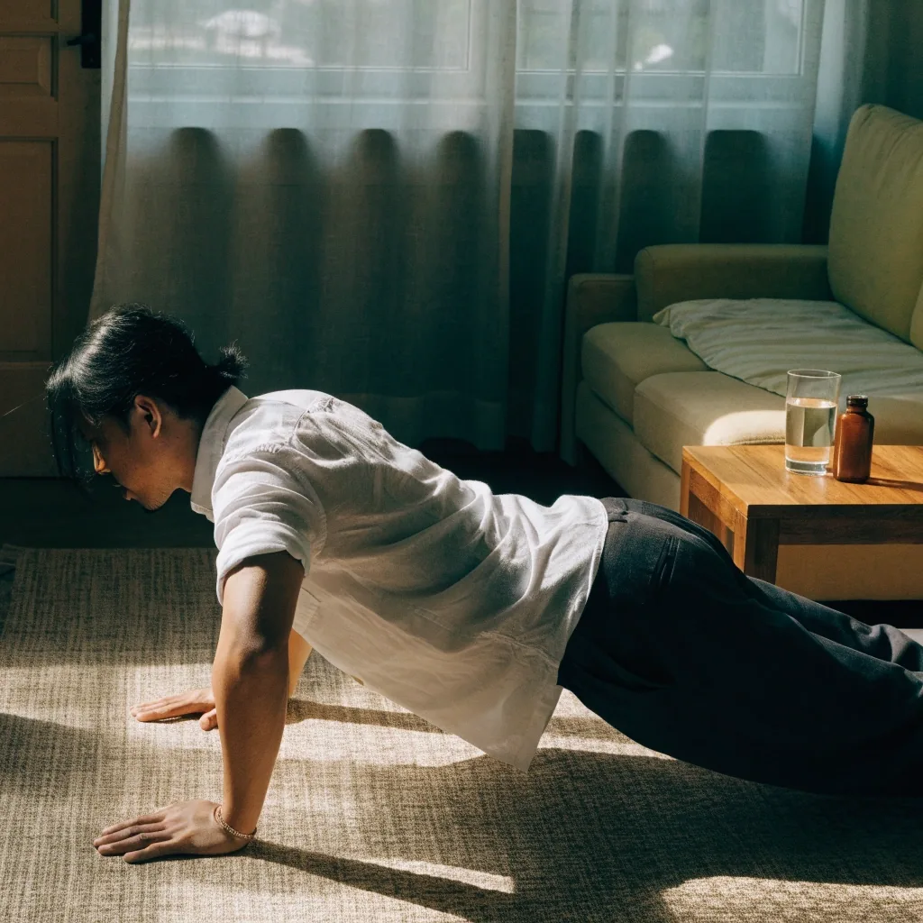 A man pulling a resistance band in a doorway of a Jakarta apartment under warm evening light